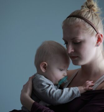 woman carrying baby with pacifier in mouth