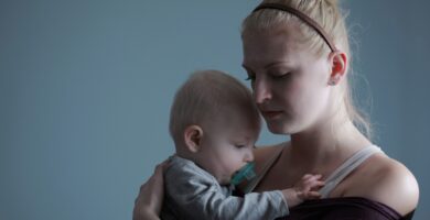 woman carrying baby with pacifier in mouth